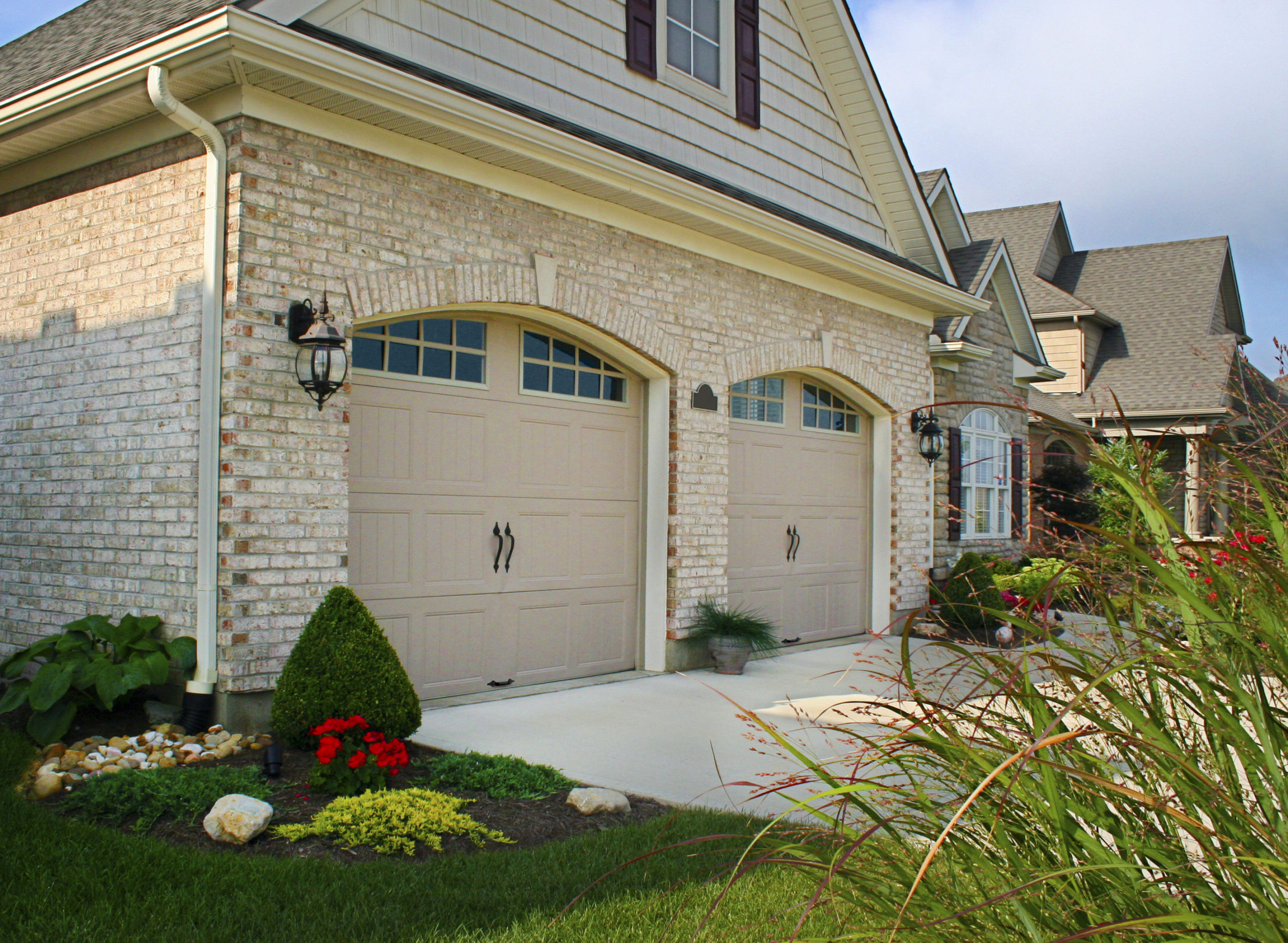 tan arched garage doors with arched windows in steel by clopay