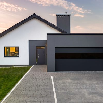 modern charcoal garage door with tinted glass on a white stucco house