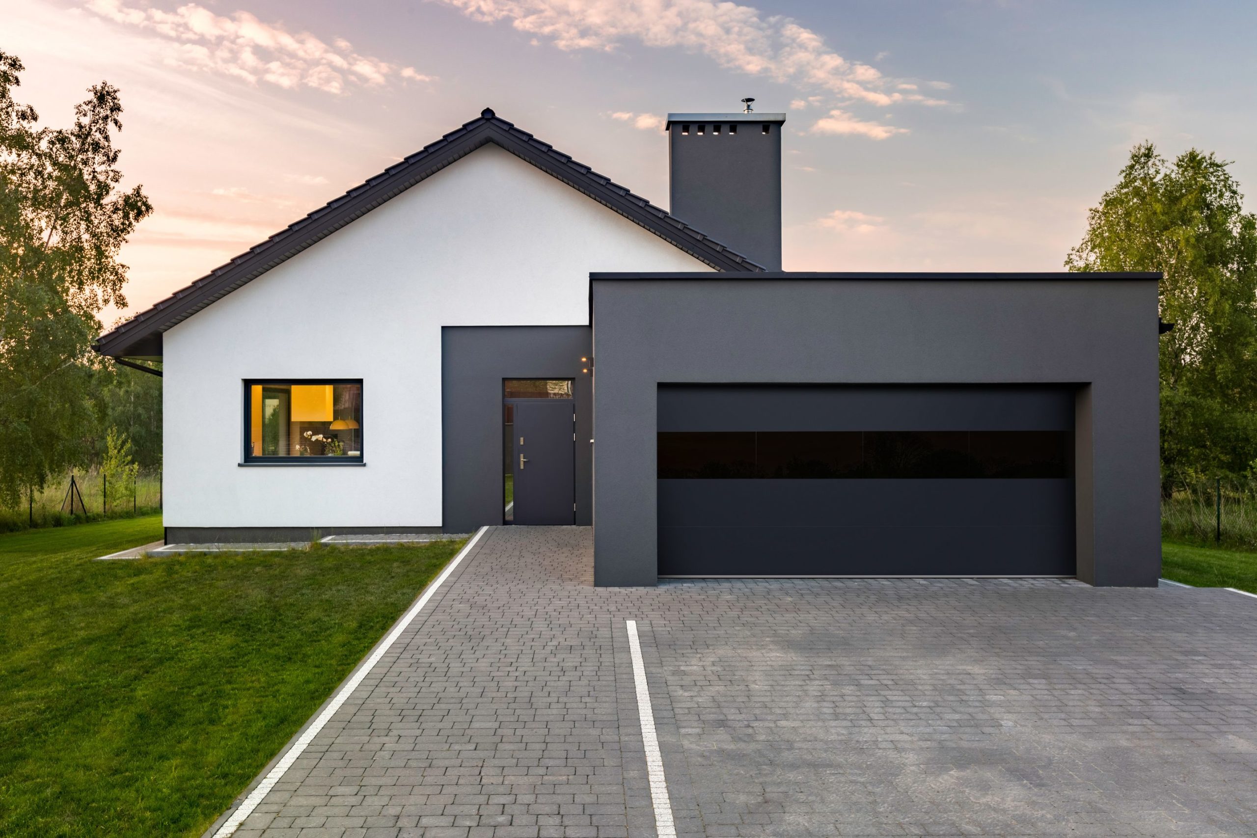 modern charcoal garage door with tinted glass on a white stucco house