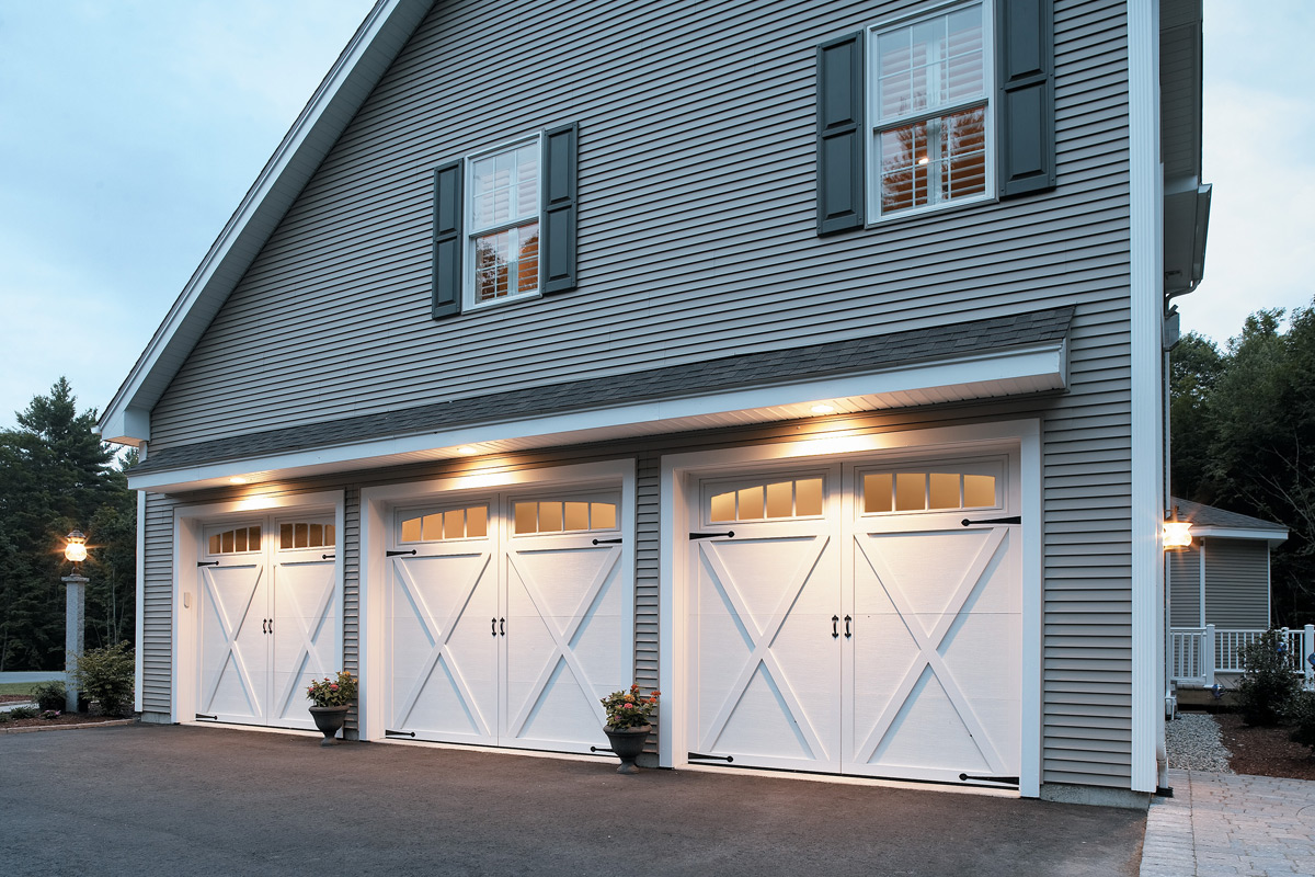 two story house with three white overhead doors courtyard collection garage doors.