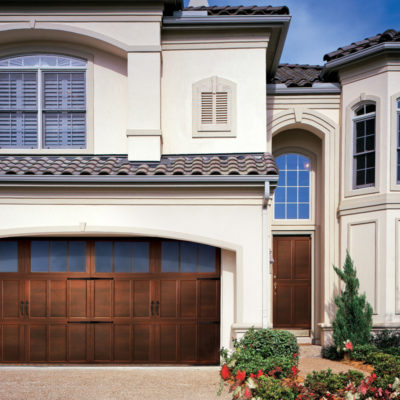 overhead carriage house garage door with woodgrain texture, stained finish, and windows panel.