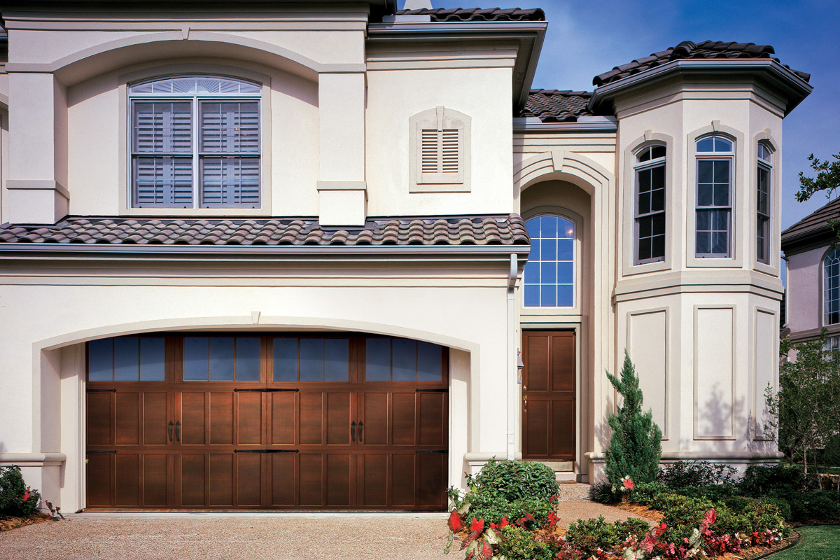 overhead carriage house garage door with woodgrain texture, stained finish, and windows panel.