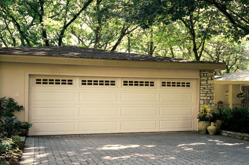 overhead traditional steel garage door with classic design, tan color, and top panel with windows