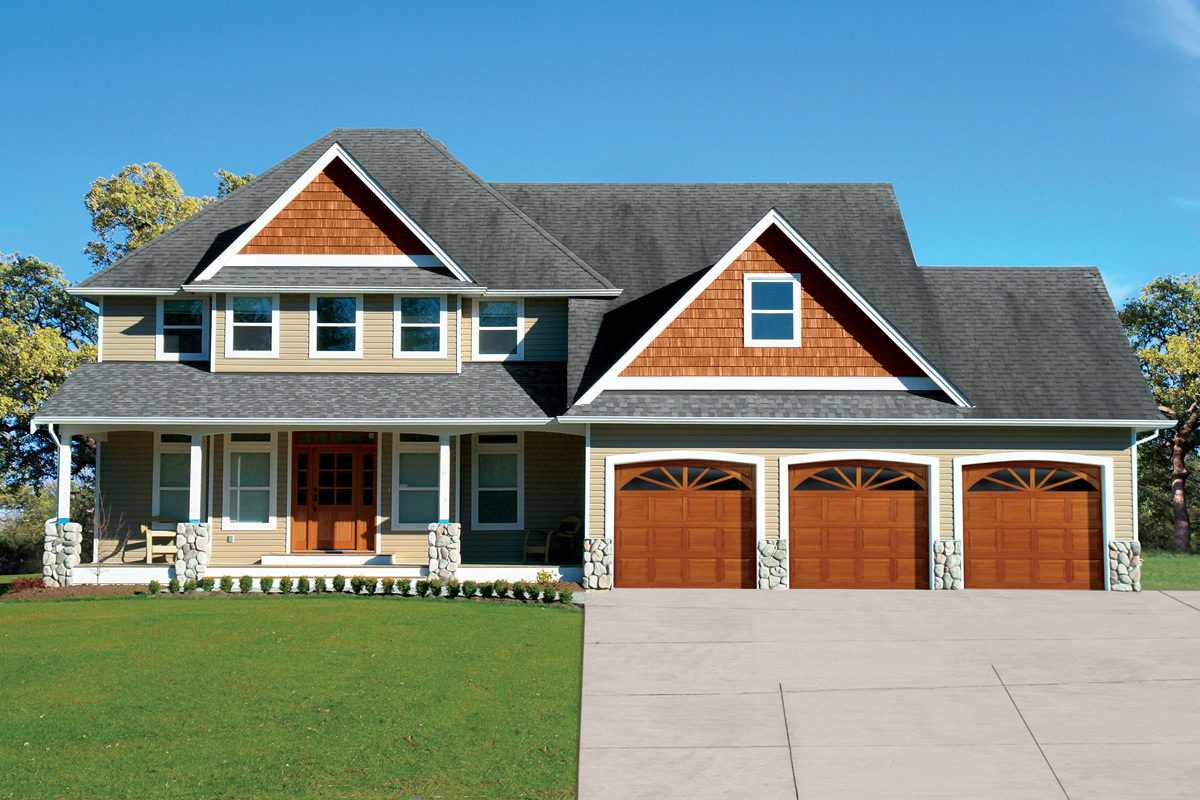 home with three overhead traditional wood garage doors