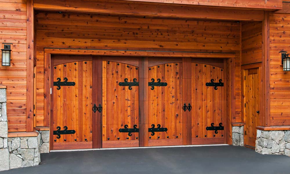 Custom traditional wood garage doors with large decorative hardware.