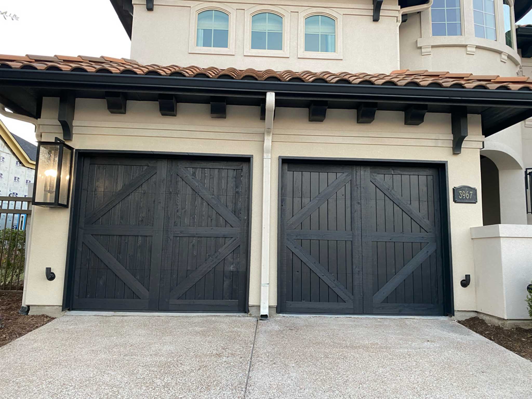 cedar garage doors painted black with tan stucco