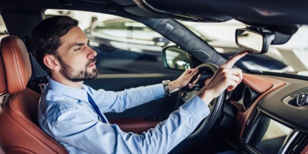 Photo of a man pressing the buttons on the rearview mirror of his vehicle.