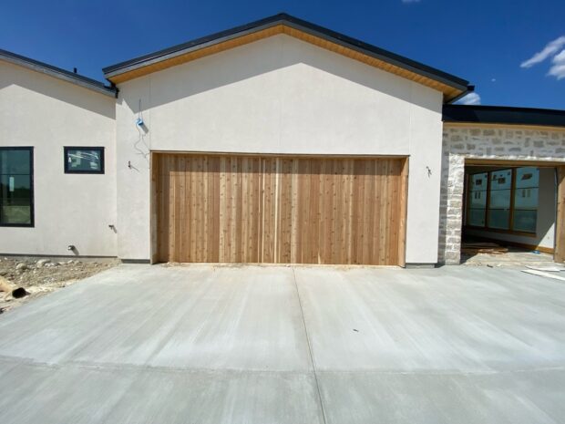 wood garage doors in vertical design, white stucco and stone home